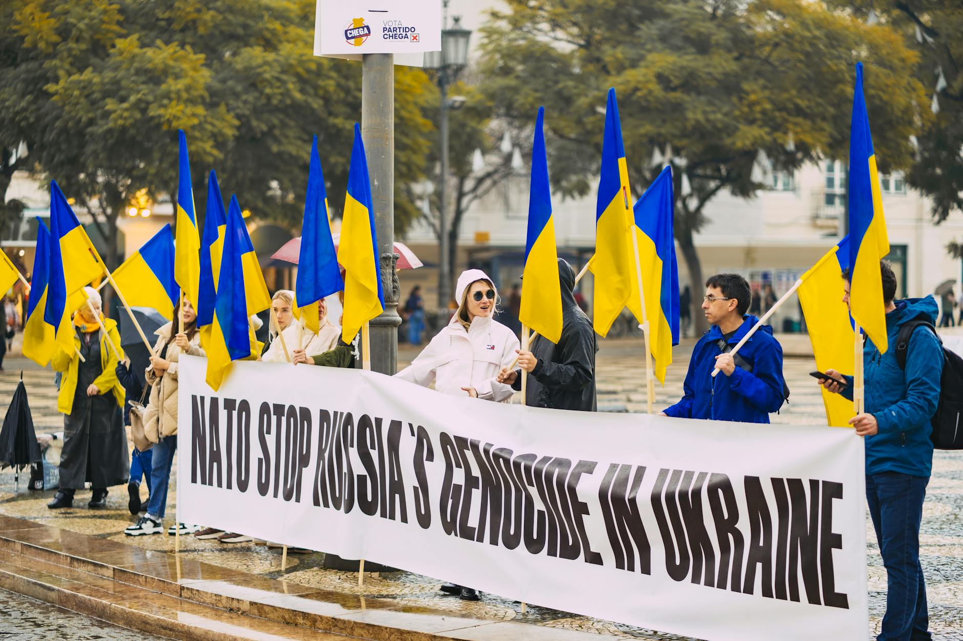 people with flags of ukraine protesting at park in city in portugal